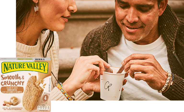 woman and man smiling and dipping snack bars in a cup